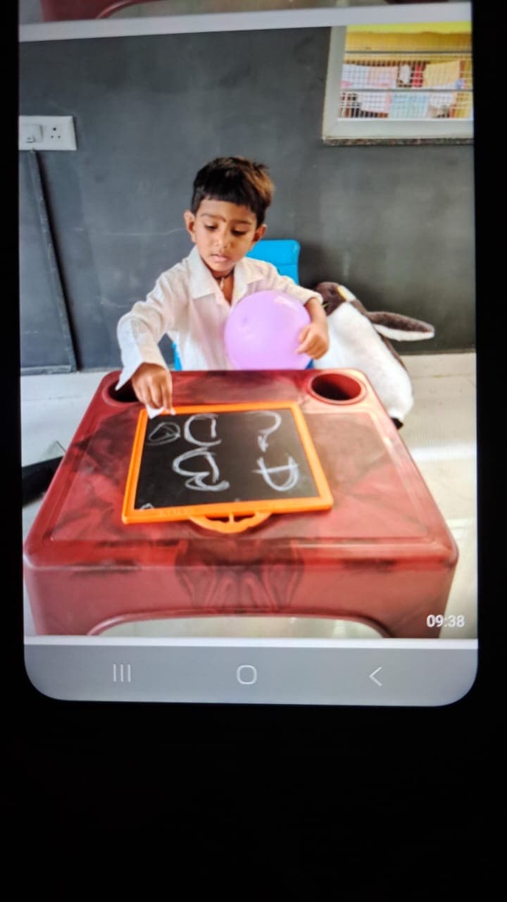 Child practicing early writing on a slate during preschool activity time