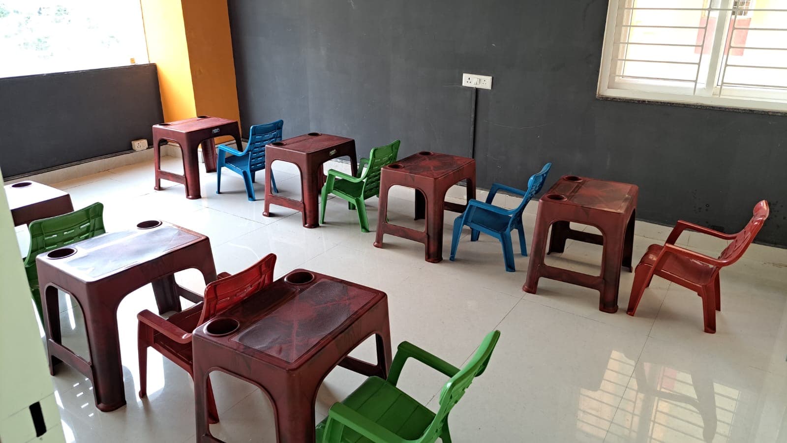Bright preschool classroom with child-sized tables and colorful chairs